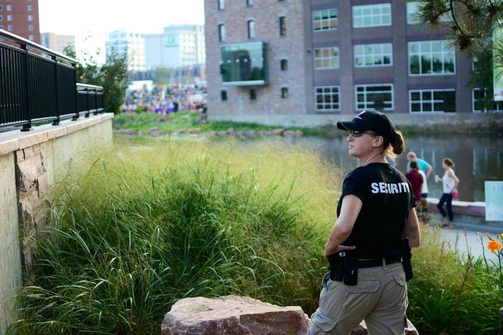 A woman in black shirt holding camera near grass.